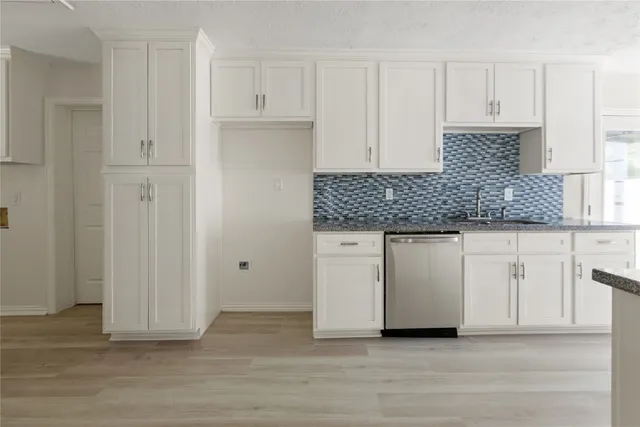 a kitchen with white cabinets and sink