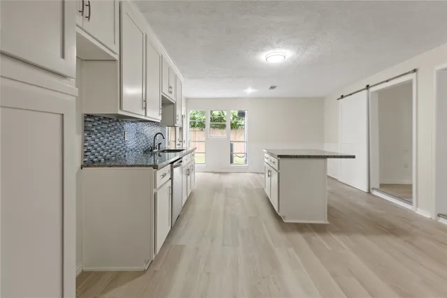 a kitchen with white cabinets and wooden floor