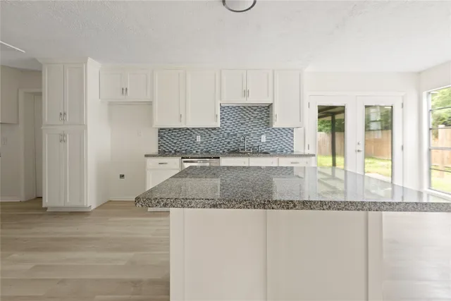 a kitchen with granite countertop a sink and white cabinets
