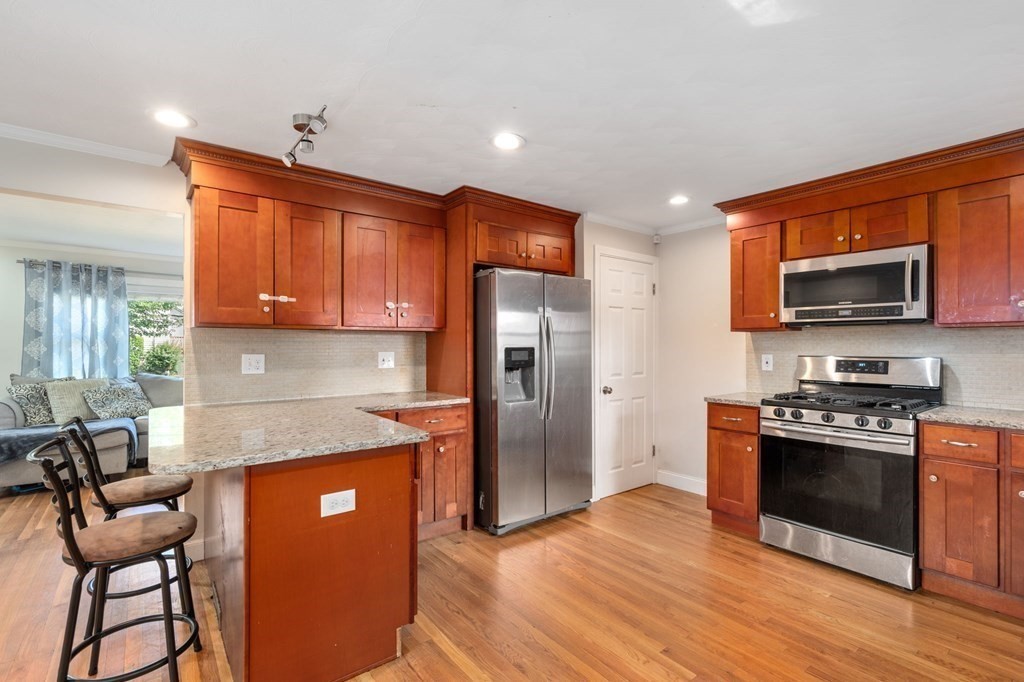 28 Rose Avenue, Unit 28 Watertown, MA 02472 - Photo 5 of 25 a kitchen with stainless steel appliances granite countertop a stove a sink dishwasher a refrigerator and a microwave oven with wooden floor