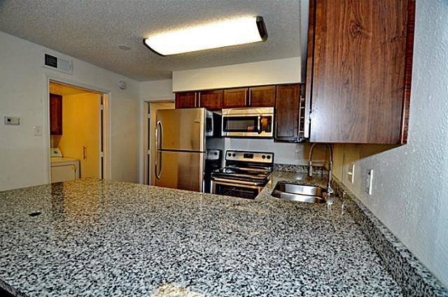 6910 Skillman Street, Unit 1007 Dallas, TX 75231 - Photo 9 of 24 a kitchen with a refrigerator and a stove top oven