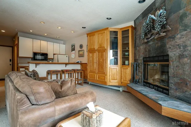 a living room with stainless steel appliances kitchen island granite countertop furniture and a fireplace