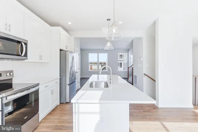 a kitchen with stainless steel appliances kitchen island granite countertop a refrigerator a stove top oven a sink and dishwasher