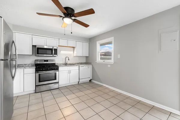 a kitchen with granite countertop a refrigerator and a stove top oven