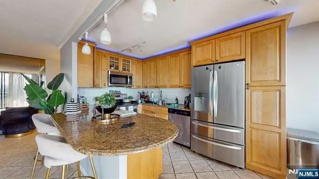 a kitchen with stainless steel appliances granite countertop a refrigerator a stove a sink and a refrigerator