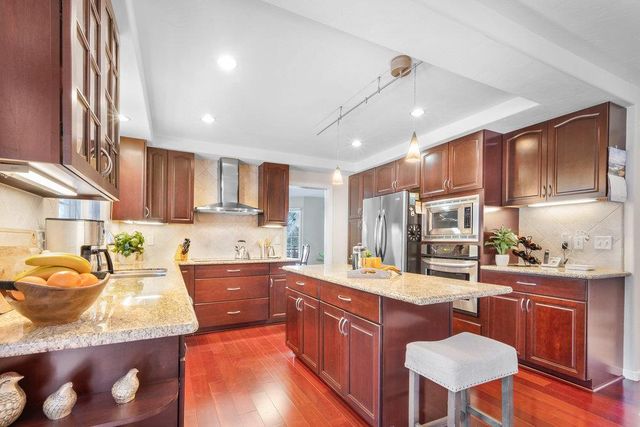 a large kitchen with kitchen island granite countertop wooden cabinets and stainless steel appliances
