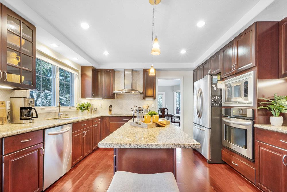 9160 Paseo Tranquillo Gilroy, CA 95020 - Photo 18 of 44 a large kitchen with stainless steel appliances granite countertop a refrigerator a sink dishwasher a stove and white cabinets with wooden floor