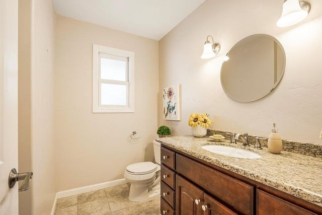 a bathroom with a granite countertop sink a toilet and a mirror