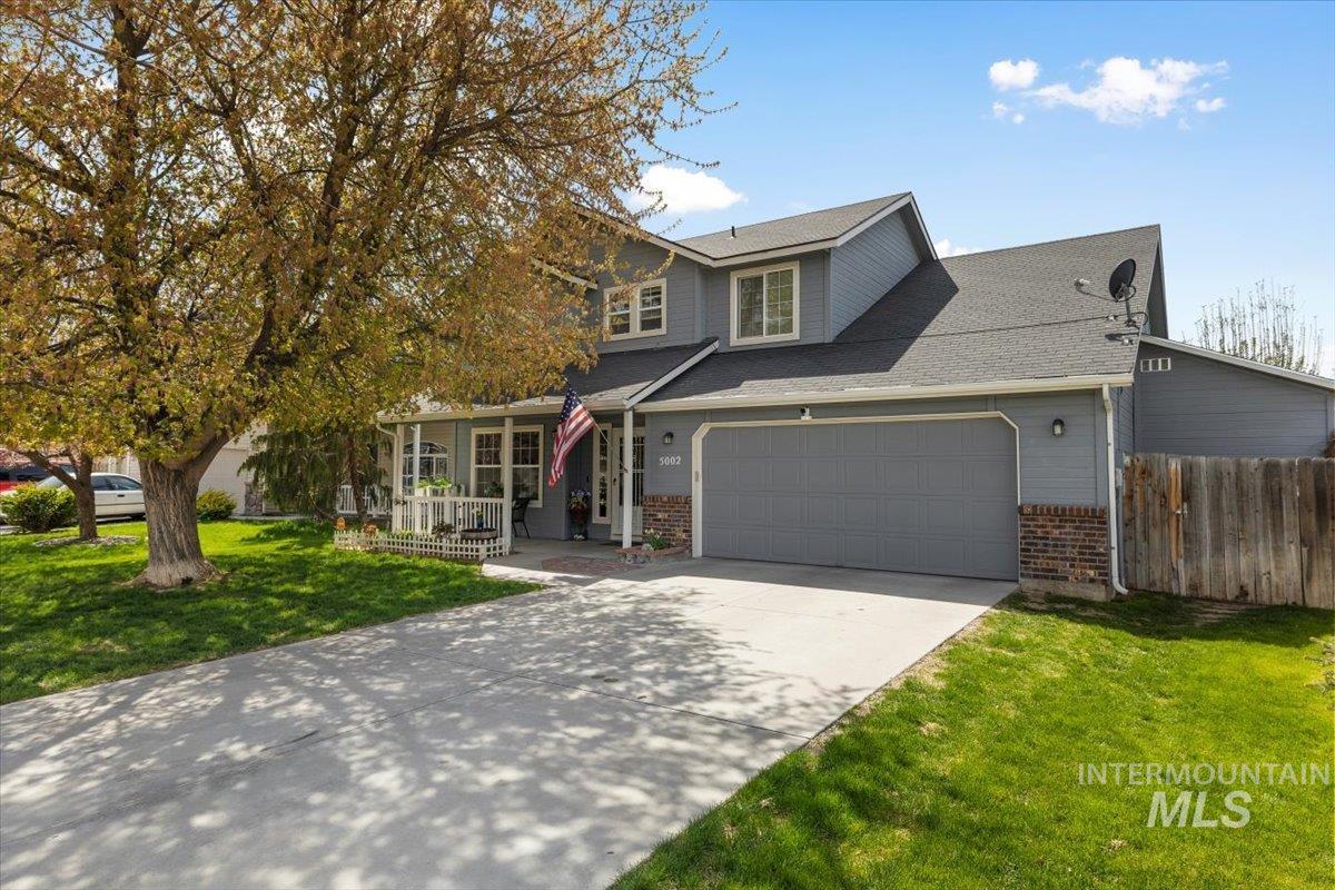 Traditional home with driveway, a porch, an attached garage, and brick siding