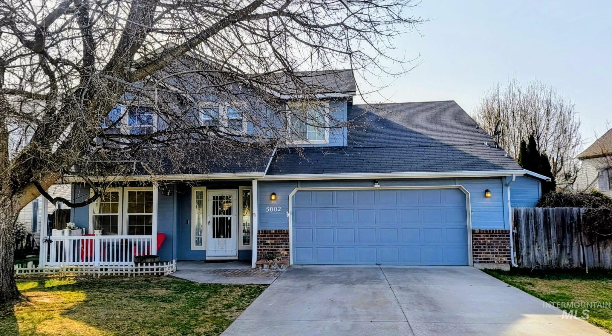 5002 Northrup Way Caldwell, ID 83607 - Photo 1 of 38 Traditional-style house with a porch, driveway, an attached garage, and brick siding