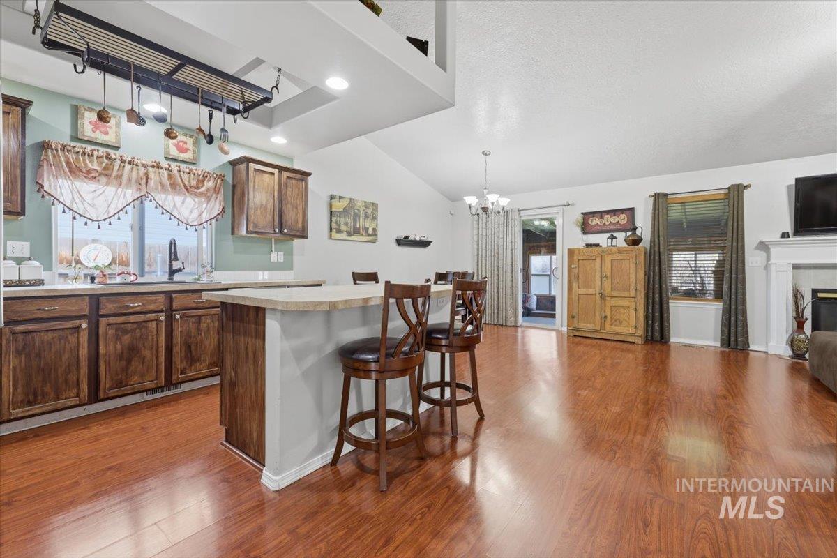 5002 Northrup Way Caldwell, ID 83607 - Photo 38 of 38 Kitchen featuring light countertops, a kitchen bar, open floor plan, a tiled fireplace, and a chandelier