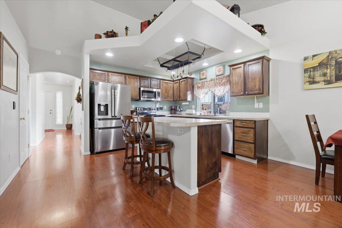 5002 Northrup Way Caldwell, ID 83607 - Photo 12 of 38 Kitchen with light countertops, stainless steel appliances, a breakfast bar area, arched walkways, and a kitchen island