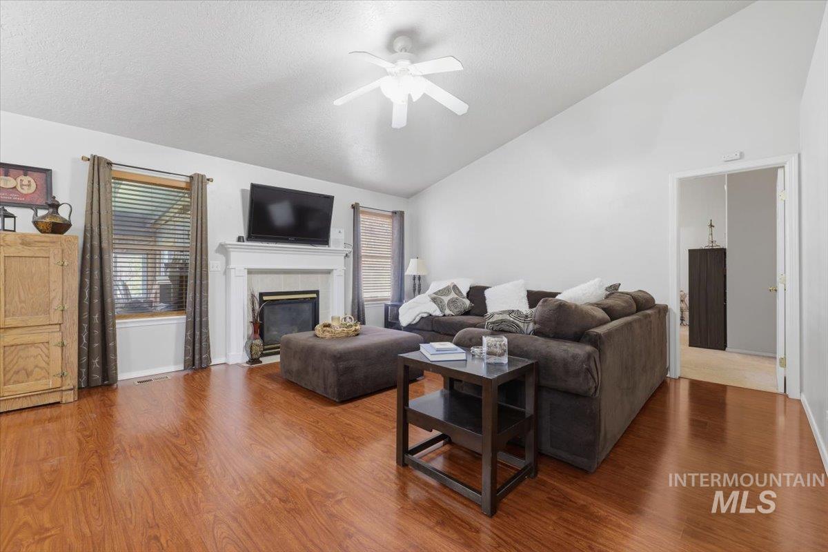 5002 Northrup Way Caldwell, ID 83607 - Photo 16 of 38 Living room with ceiling fan, wood finished floors, a fireplace, and a high textured ceiling
