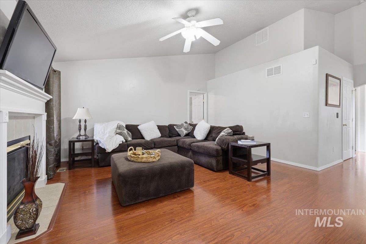 5002 Northrup Way Caldwell, ID 83607 - Photo 17 of 38 Living room featuring a ceiling fan, wood finished floors, a tile fireplace, and a high textured ceiling