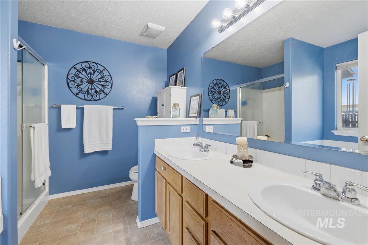 5002 Northrup Way Caldwell, ID 83607 - Photo 23 of 38 Bathroom featuring a stall shower, a textured ceiling, and double vanity