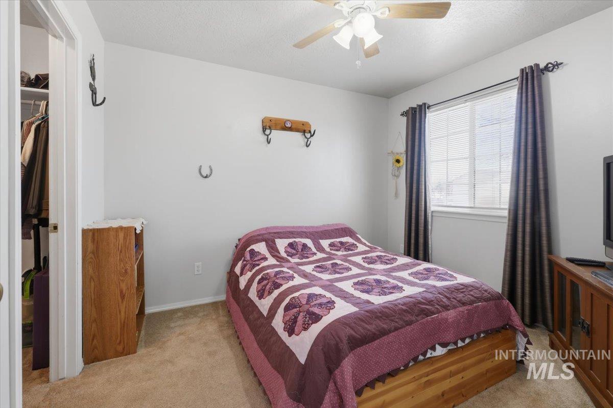 5002 Northrup Way Caldwell, ID 83607 - Photo 27 of 38 Bedroom featuring light carpet, a textured ceiling, a ceiling fan, and a walk in closet