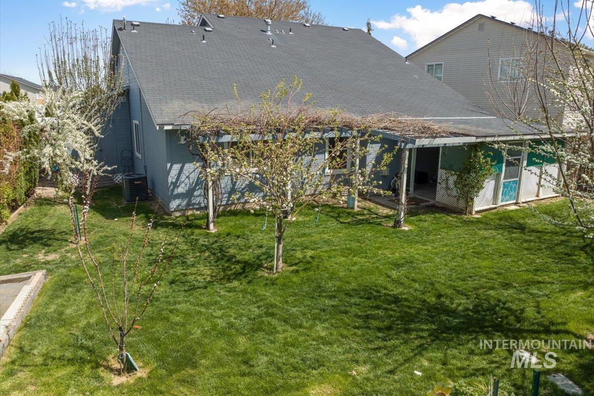 5002 Northrup Way Caldwell, ID 83607 - Photo 32 of 38 Back of house featuring a shingled roof, a yard, and a patio area