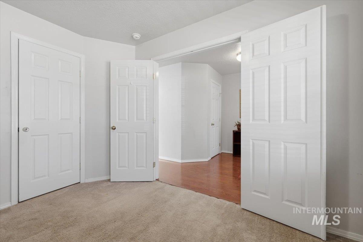 5002 Northrup Way Caldwell, ID 83607 - Photo 8 of 38 Unfurnished bedroom with light carpet and a textured ceiling