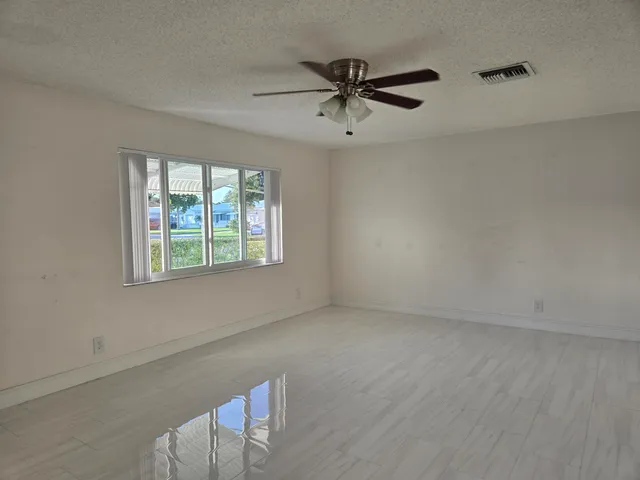 an empty room with windows and fan