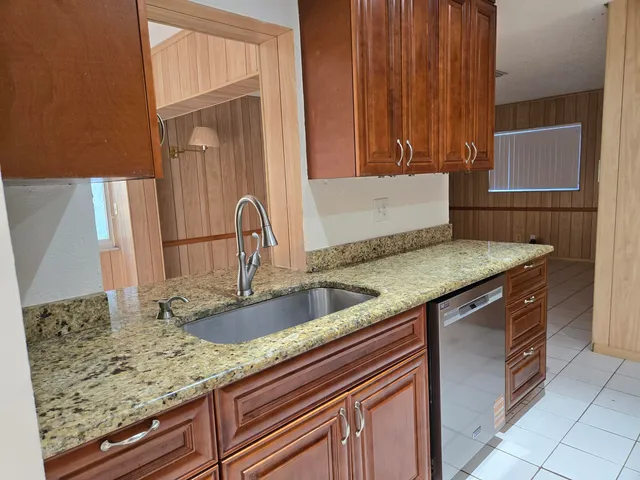 a kitchen with granite countertop a sink and a wooden cabinets