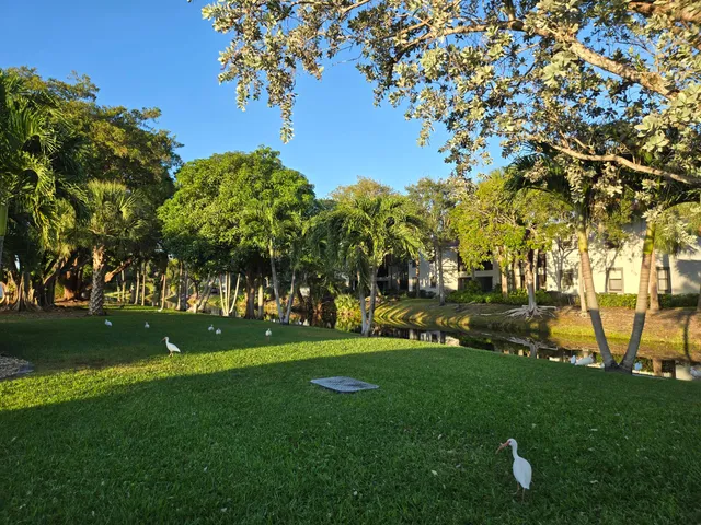 a view of a refrigerator in kitchen and an empty room in wooden floor