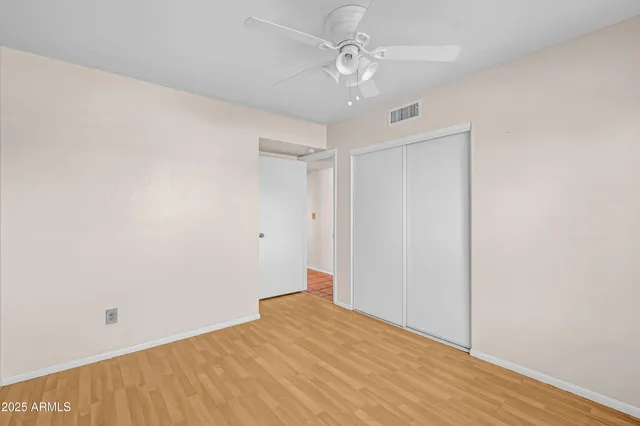 an empty room with windows and fan