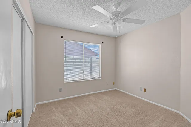 an empty room with a chandelier fan and closet area