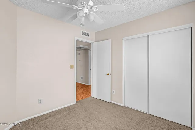 an empty room with windows and fan