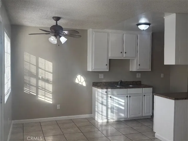 a kitchen with granite countertop white cabinets stainless steel appliances a sink and a window