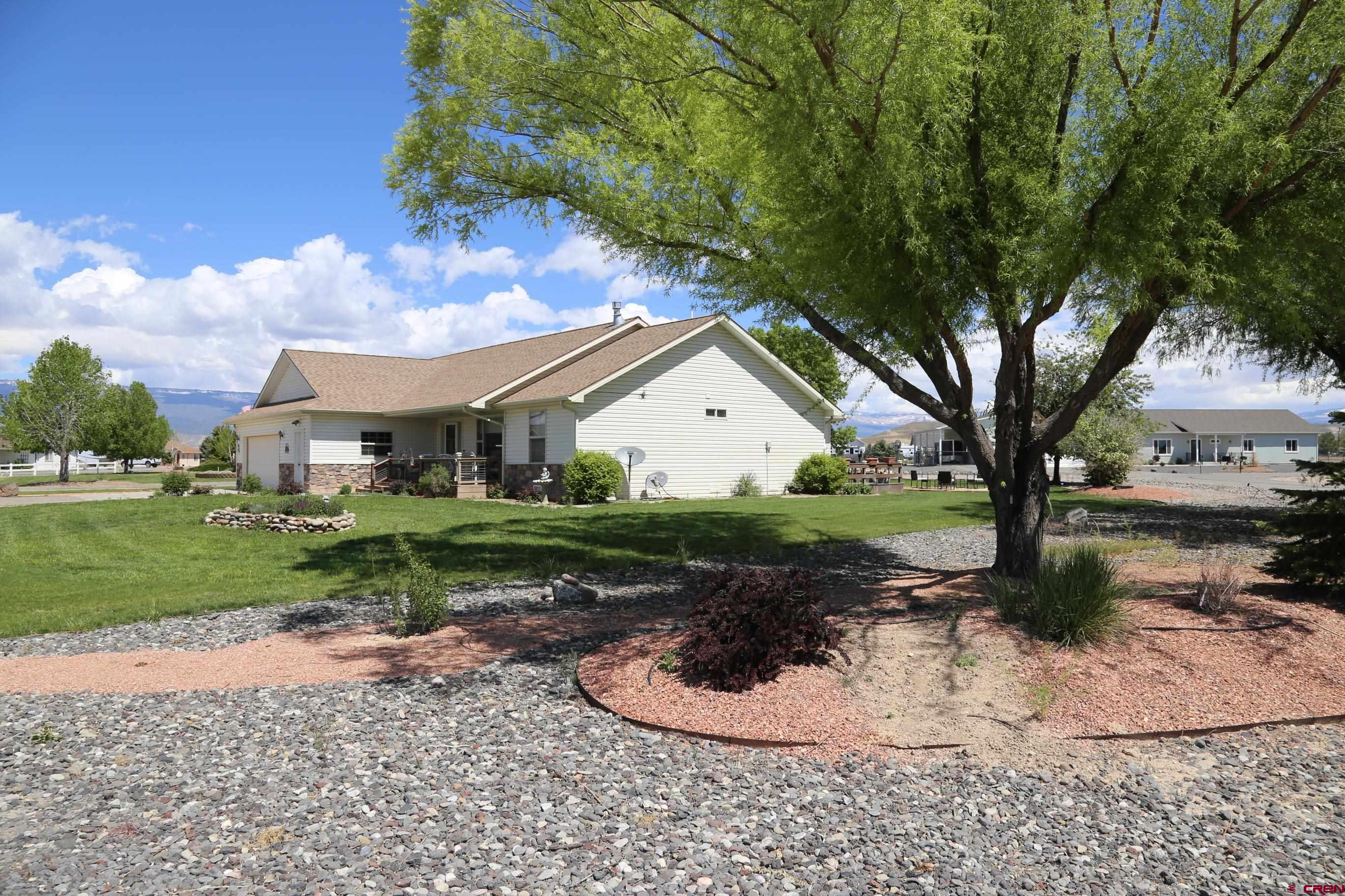 20287 Fox Ridge Drive Austin, CO 81410 - Photo 11 of 16 a view of a white house next to a yard with big trees and plants