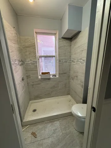 a bathroom with a granite countertop bathtub shower and a toilet