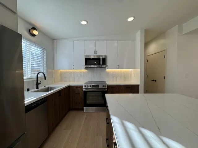 a kitchen with kitchen island granite countertop a sink dishwasher stove and refrigerator with wooden floor
