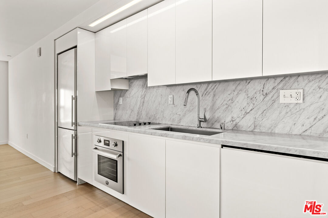 1050 South Grand Avenue, Unit 1405 Los Angeles, CA 90015 - Photo 2 of 11 a kitchen with granite countertop white cabinets and white appliances