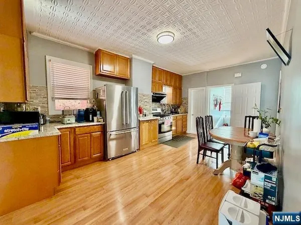 a kitchen with stainless steel appliances wooden floor and a refrigerator