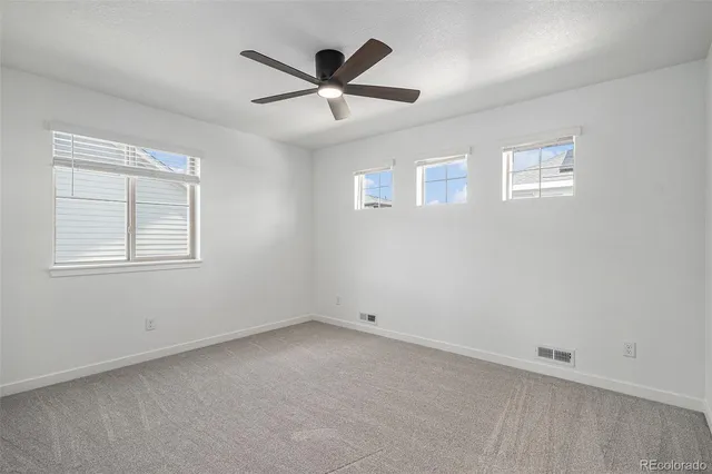 an empty room with a window and ceiling fan