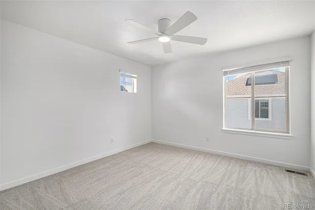 an empty room with wooden floor chandelier fan and windows