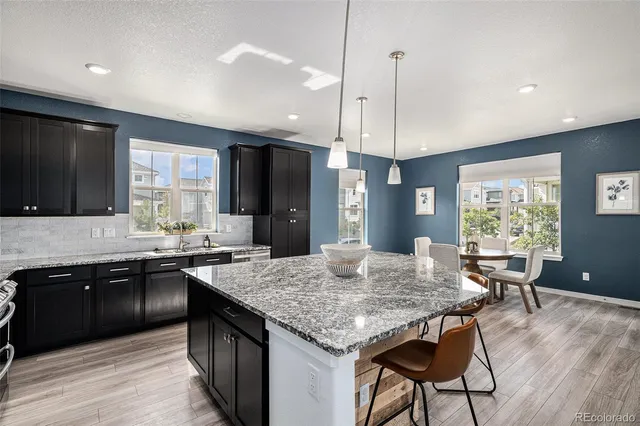 a kitchen with granite countertop kitchen island stainless steel appliances a sink stove and wooden floor