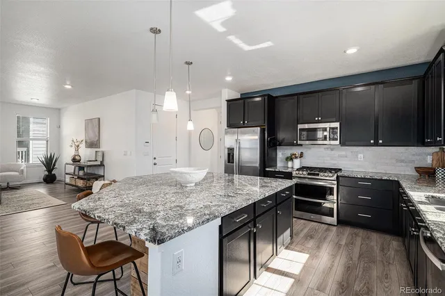 a kitchen with kitchen island granite countertop a stove a sink a oven a dining table and chairs