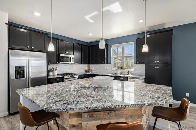 a kitchen with stainless steel appliances kitchen island granite countertop a sink refrigerator and cabinets
