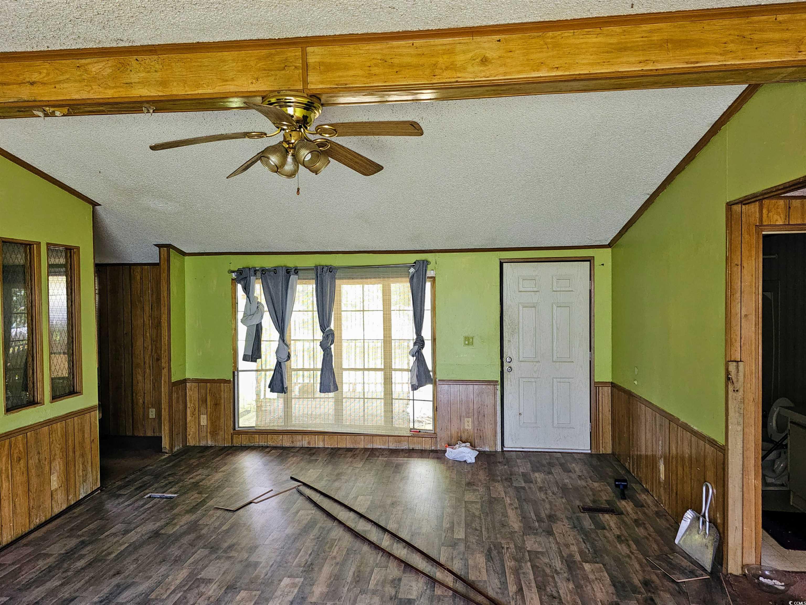 827 1/2 North Firetower Road Florence, SC 29506 - Photo 11 of 29 Unfurnished living room with wood walls, a textured ceiling, wainscoting, wood finished floors, and ceiling fan