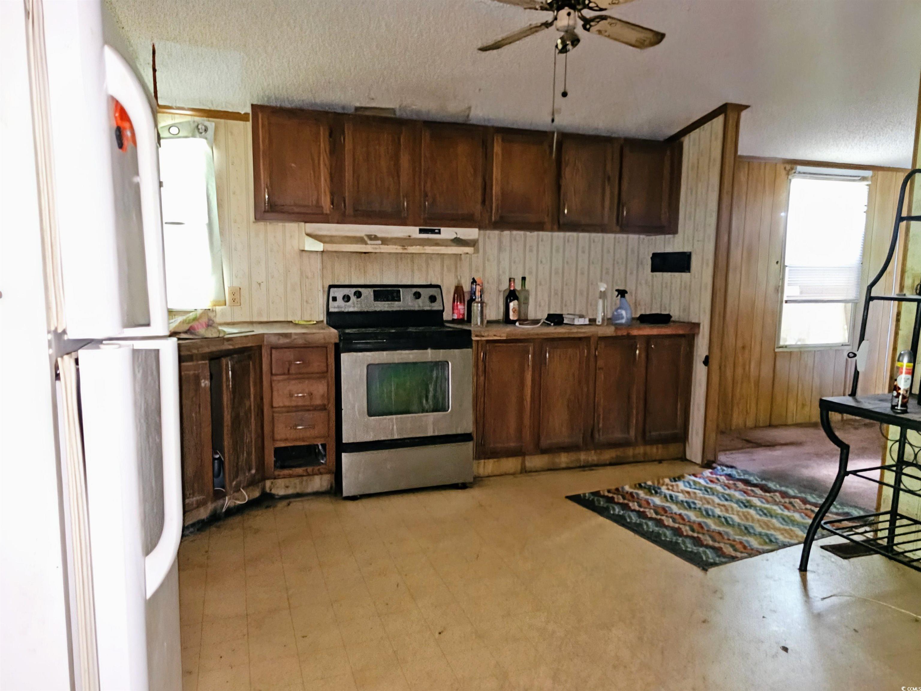 827 1/2 North Firetower Road Florence, SC 29506 - Photo 7 of 29 Kitchen with wooden walls, stainless steel electric range oven, freestanding refrigerator, light flooring, and a ceiling fan