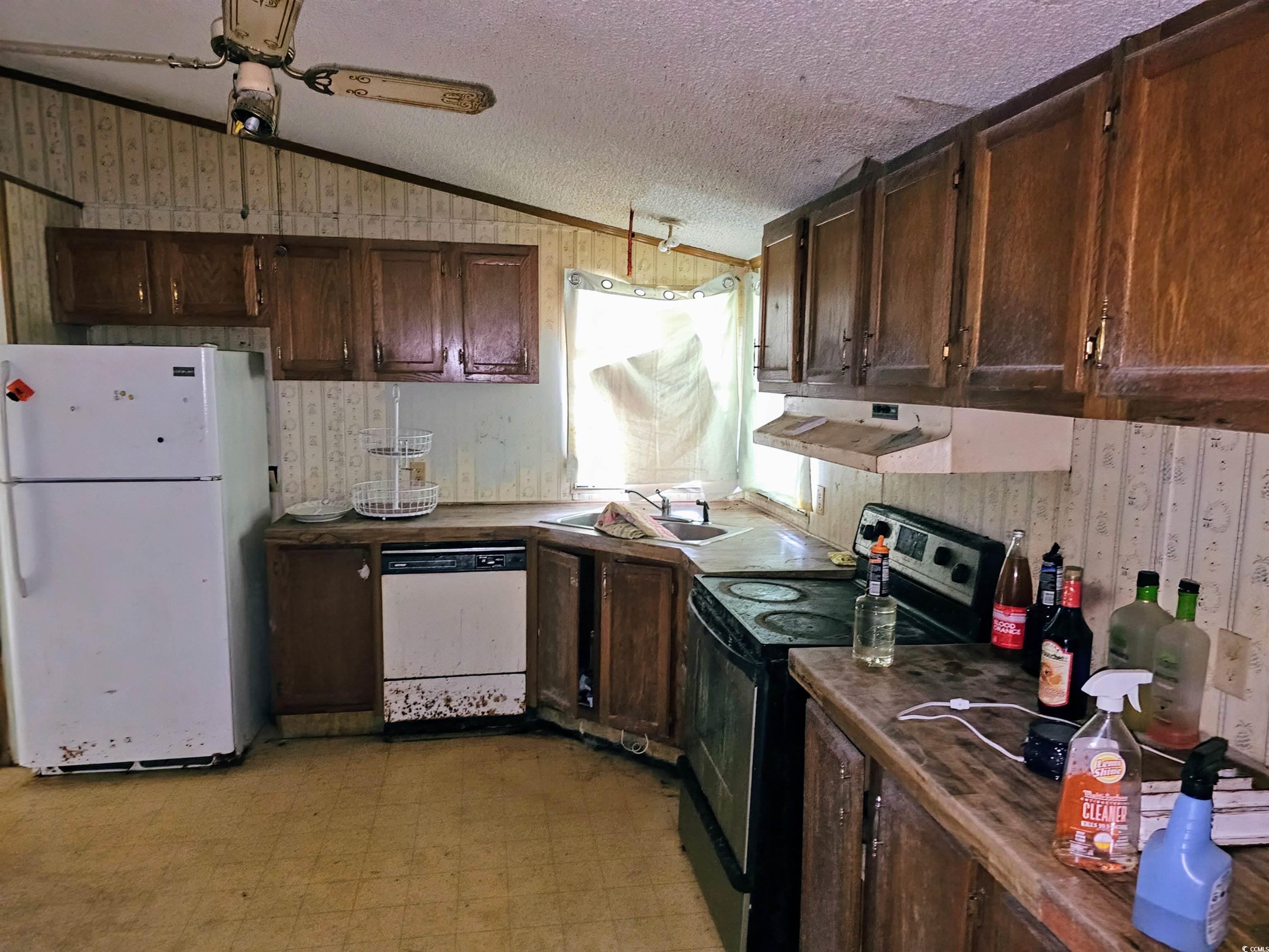 827 1/2 North Firetower Road Florence, SC 29506 - Photo 8 of 29 Kitchen with wallpapered walls, light floors, lofted ceiling, white appliances, and dark countertops