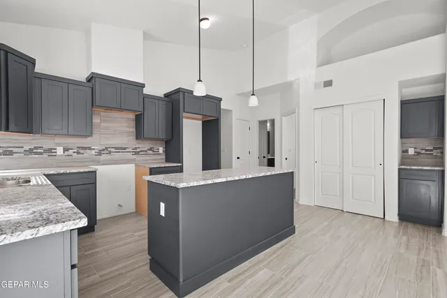 a kitchen with stainless steel appliances kitchen island granite countertop a wooden floor a stove a sink a refrigerator and wooden floor