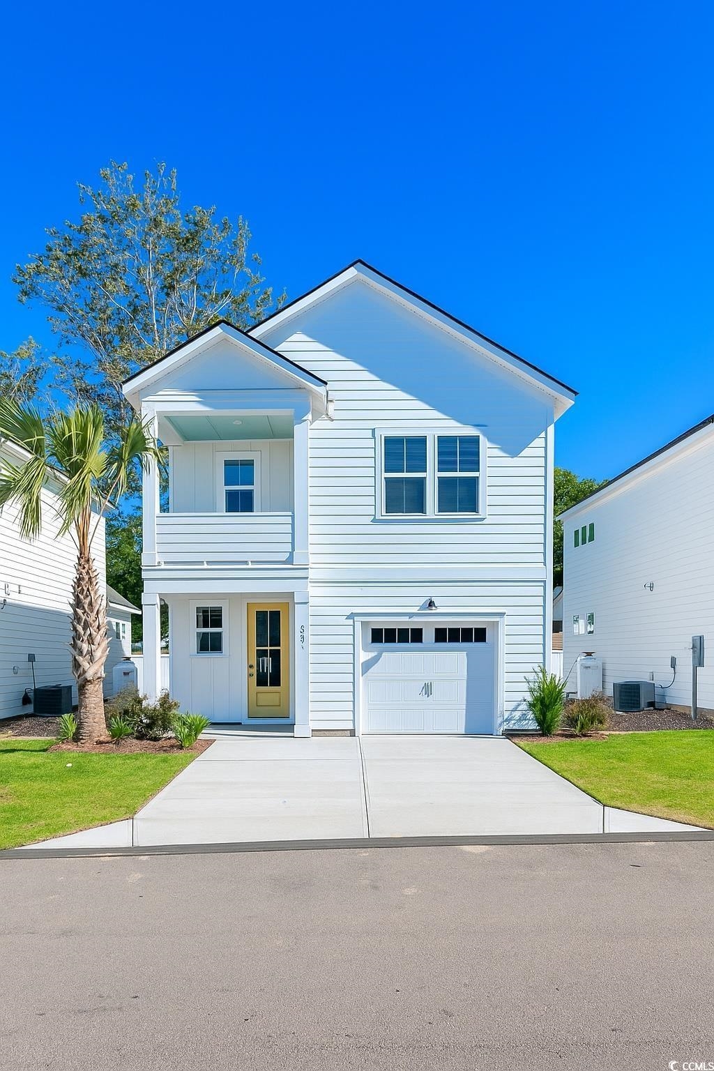 View of front facade with a balcony, driveway, board and batten siding, and an attached garage