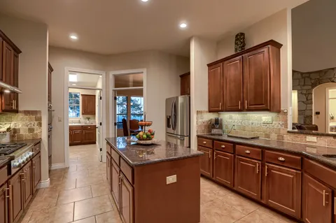 a kitchen with kitchen island granite countertop a sink stove and cabinets