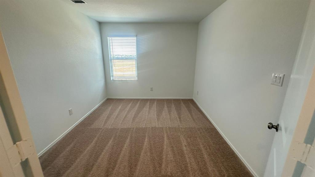 192 Rodney Boat Road Kyle, TX 78640 - Photo 35 of 38 A well-lit bedroom provides a cozy retreat, featuring plush carpeting and a bright window.