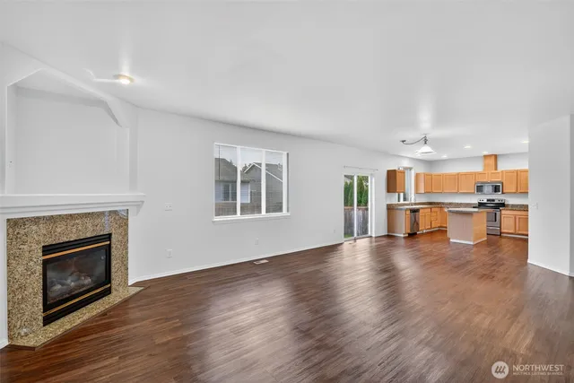 a view of an empty room with wooden floor and a fireplace