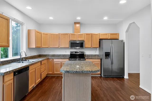 a kitchen with granite countertop a refrigerator and a stove top oven