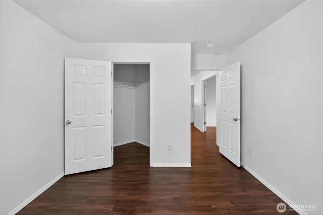 a view of an empty room with wooden floor and closet