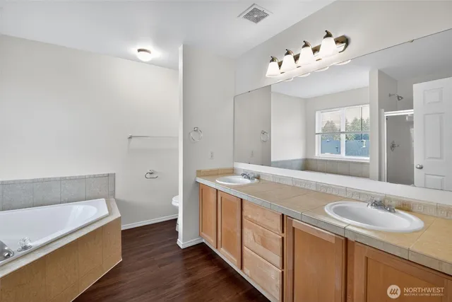 a spacious bathroom with a granite countertop sink a mirror and a bathtub
